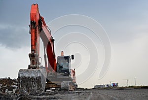 A heavy excavator in a working at granite quarry unloads old concrete stones for crushing and recycling to gravel or cement.