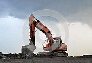 A heavy excavator in a working at granite quarry unloads old concrete stones for crushing and recycling to gravel or cement.