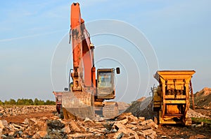 A heavy excavator in a working at granite quarry unloads old concrete stones for crushing and recycling to gravel or cement.