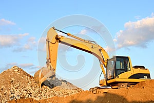 A heavy excavator in a working at granite quarry unloads old concrete stones for crushing and recycling to gravel or cement.