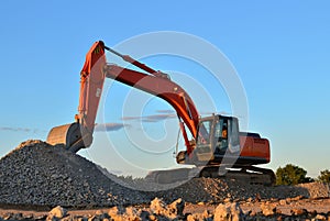 Heavy excavator in a working at granite quarry unloads old concrete stones for crushing and recycling to gravel or cement. Special