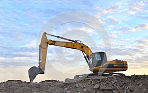 A heavy excavator in a working at granite quarry unloads old concrete stones for crushing and recycling to gravel or cement. Toned