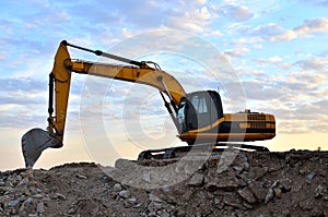 A heavy excavator in a working at granite quarry unloads old concrete stones for crushing and recycling to gravel or cement. Toned