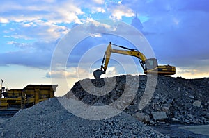 Heavy excavator working in quarry on a background of sunset and blue sky.