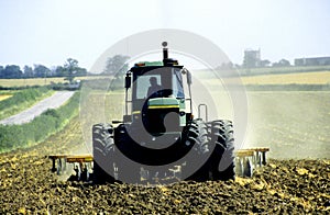 UK agriculture. John Deere tractor tining field arable farmland.