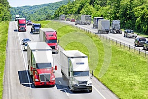 A heavy flow of 18-wheelers peppered with cars and SUVs roll down a Tennessee interstate highway photo