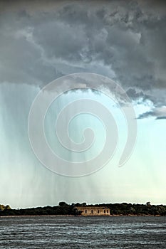 Heavy gray cloud with rain over the distant ruins of building