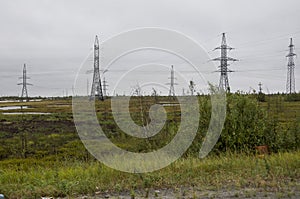 Heavy grey clouds in the cold autumn sky over green fields, trees, forests, streams. Before storm. Electric poles photo