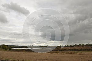 Heavy grey clouds in the cold autumn sky over rivers, fields, forests and mountains