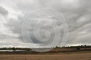 Heavy grey clouds in the cold autumn sky over rivers, fields, forests and mountains