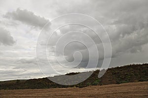 Heavy grey clouds in the cold autumn sky over rivers, fields, forests and mountains