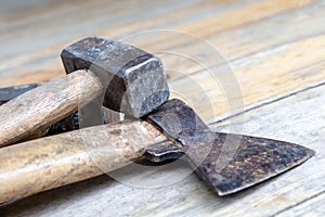 Heavy hammer lies on an ax. An old builder tool lies on a wooden background