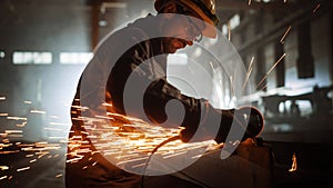 Heavy Industry Engineering Factory Interior with Industrial Worker Using Angle Grinder and Cutting