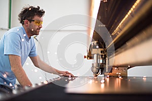 Within heavy industry. A man works in a modern factory on a CNC machine. Selective focus