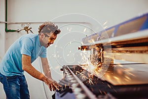 Within heavy industry. A man works in a modern factory on a CNC machine. Selective focus