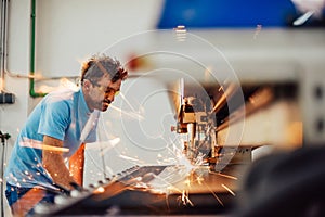 Within heavy industry. A man works in a modern factory on a CNC machine. Selective focus