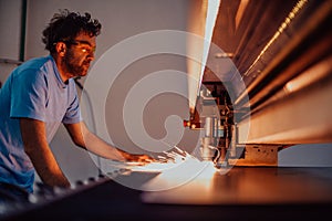 Within heavy industry. A man works in a modern factory on a CNC machine. Selective focus