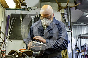 Heavy industry worker cutting steel with angle grinder at car service