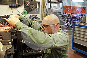 Heavy industry worker cutting steel with angle grinder at car service