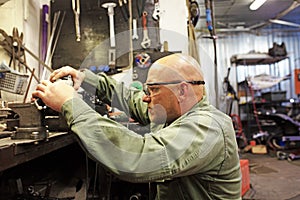 Heavy industry worker cutting steel with angle grinder at car service