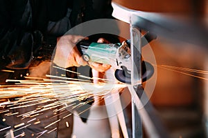 Heavy industry worker cutting steel with angle grinder on construction site