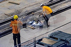Heavy industry worker cutting steel Light rail with an angle grinder in workshop