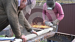 Heavy industry worker cutting steel pipe with angle grinder in workshop