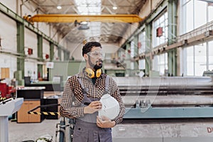 Heavy industry worker with safety headphones and hard hat in industrial factory