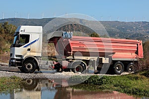 Heavy lorry or truck drives through small river