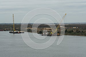 Heavy machinery crane on floating barge near the left bank of the Savannah River.