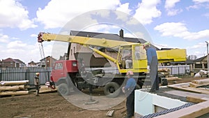 Heavy machinery and the crew of male carpenters at the construction site. Clip. Rear view of workers and machinery on