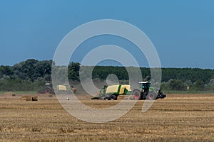 Heavy machinery in the field performs agricultural work during the summer