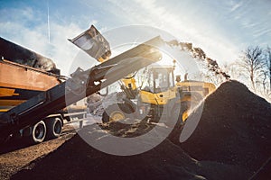 Heavy machinery moving earth and biomass in compost works