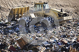 Heavy machinery shredding garbage in an open air landfill. Pollution