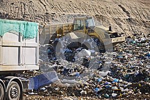 Heavy machinery shredding garbage in an open air landfill. Pollution