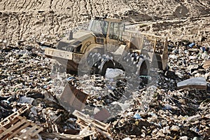 Heavy machinery shredding garbage in an open air landfill. Pollution