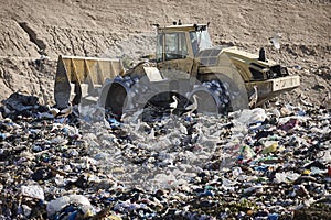 Heavy machinery shredding garbage in an open air landfill. Pollution