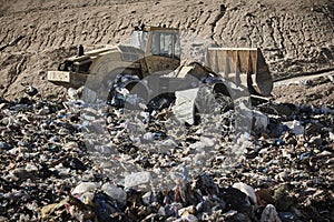 Heavy machinery shredding garbage in an open air landfill. Pollution