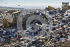 Heavy machinery shredding garbage in an open air landfill. Pollution