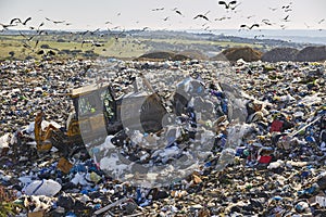 Heavy machinery shredding garbage in an open air landfill. Pollution