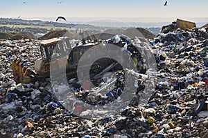 Heavy machinery shredding garbage in an open air landfill. Pollution