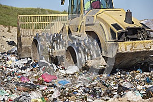 Heavy machinery shredding garbage in an open air landfill. Pollution