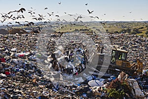 Heavy machinery shredding garbage in an open air landfill. Pollution