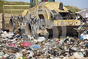 Heavy machinery shredding garbage in an open air landfill. Pollution