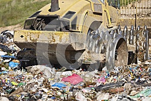 Heavy machinery shredding garbage in an open air landfill. Pollution