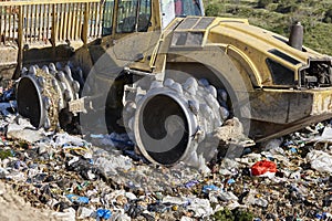 Heavy machinery shredding garbage in an open air landfill. Pollution