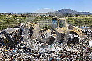 Heavy machinery shredding garbage in an open air landfill. Pollution