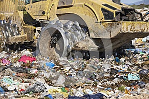 Heavy machinery shredding garbage in an open air landfill. Pollution management