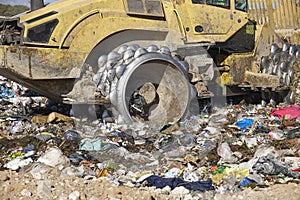 Heavy machinery shredding garbage in an open air landfill. Pollution management