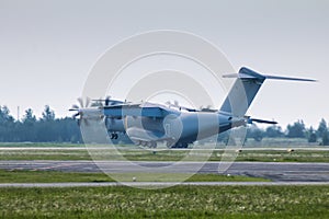 Heavy military transport turboprop aircraft touching the runway